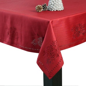 May include: Red tablecloth with a pine cone design. The tablecloth has a scalloped edge and is made of a soft, woven fabric.