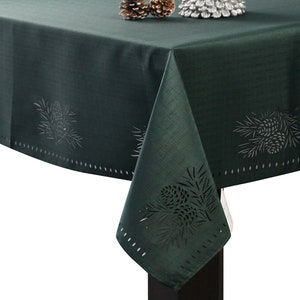 May include: A dark green tablecloth with a pine cone design. The tablecloth has a scalloped edge and is made of a soft, textured fabric.