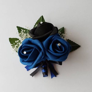 May include: A buttonhole with three fabric roses, two blue and one black, with white baby's breath and black and blue ribbon.