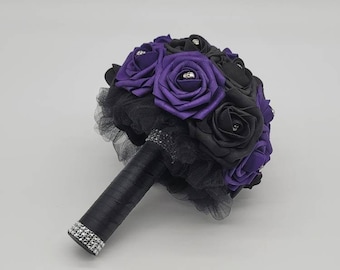 May include: A bridal bouquet with purple and black silk roses, black tulle, and a black satin ribbon with rhinestones.