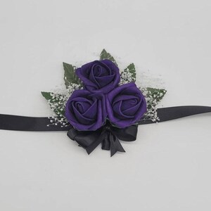 Wrist corsage in dark purple rose buds, black ribbon, 5 faux leaves and finished with baby's breath.