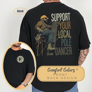 May include: Black t-shirt with a graphic of a lineman climbing a utility pole. The text on the shirt reads "Support Your Local Pole Dancer".