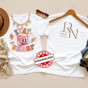 May include: White t-shirts with graphic designs, one with "Stay Sharp" text and a cartoon character, the other with a logo. Accessories include a brown hat, sunglasses, and leopard print heels.