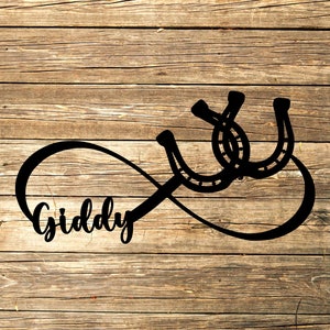May include: Black silhouette of an infinity symbol with the word "Giddy" inside and two horseshoes on top of the symbol. The image is on a wood background.