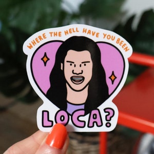 Op de afbeelding: Een sticker met een cartoon illustratie van een persoon met lang zwart haar, in een roze hart met de tekst "WHERE THE HELL HAVE YOU BEEN" boven de illustratie. Het woord "LOCA?" staat eronder.