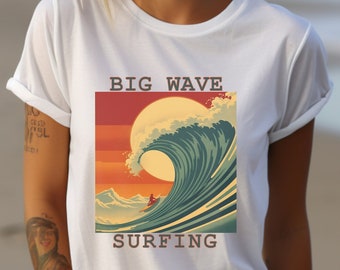May include: White t-shirt with a retro-style graphic of a large ocean wave, a setting sun, and the words "BIG WAVE SURFING." The shirt is worn by a person on a beach with the ocean in the background.