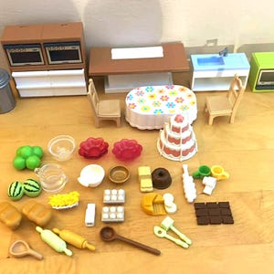 May include: A collection of miniature toy kitchen and dining room furniture and accessories. Includes a double oven, table, sink, microwave, chairs, cake, food items, and utensils. The items are made of plastic and are in various colors.