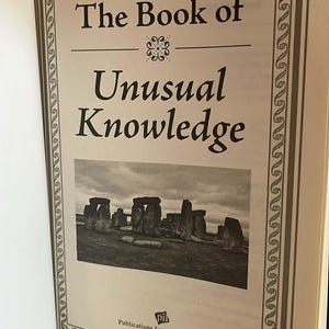 Puede incluir: Libro abierto titulado "The Book of Unusual Knowledge". La portada presenta el t&iacute;tulo en fuente serif, un borde decorativo y una imagen en blanco y negro de Stonehenge. El logotipo del editor est&aacute; en la parte inferior.
