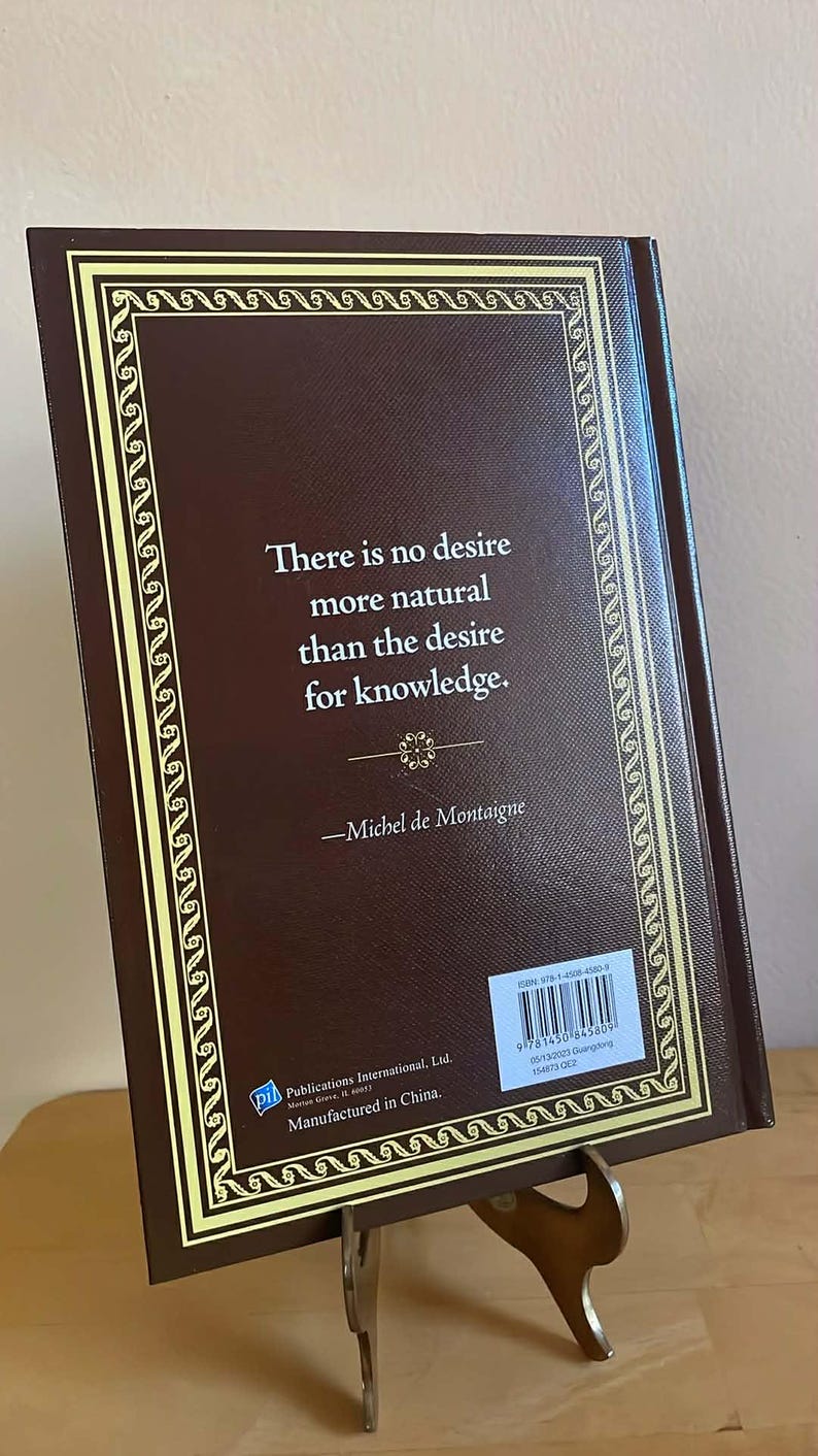 Puede incluir: Un libro de tapa dura con una cubierta marr&oacute;n y un borde decorativo dorado. El libro muestra una cita de Michel de Montaigne: "No hay deseo m&aacute;s natural que el deseo de conocimiento."