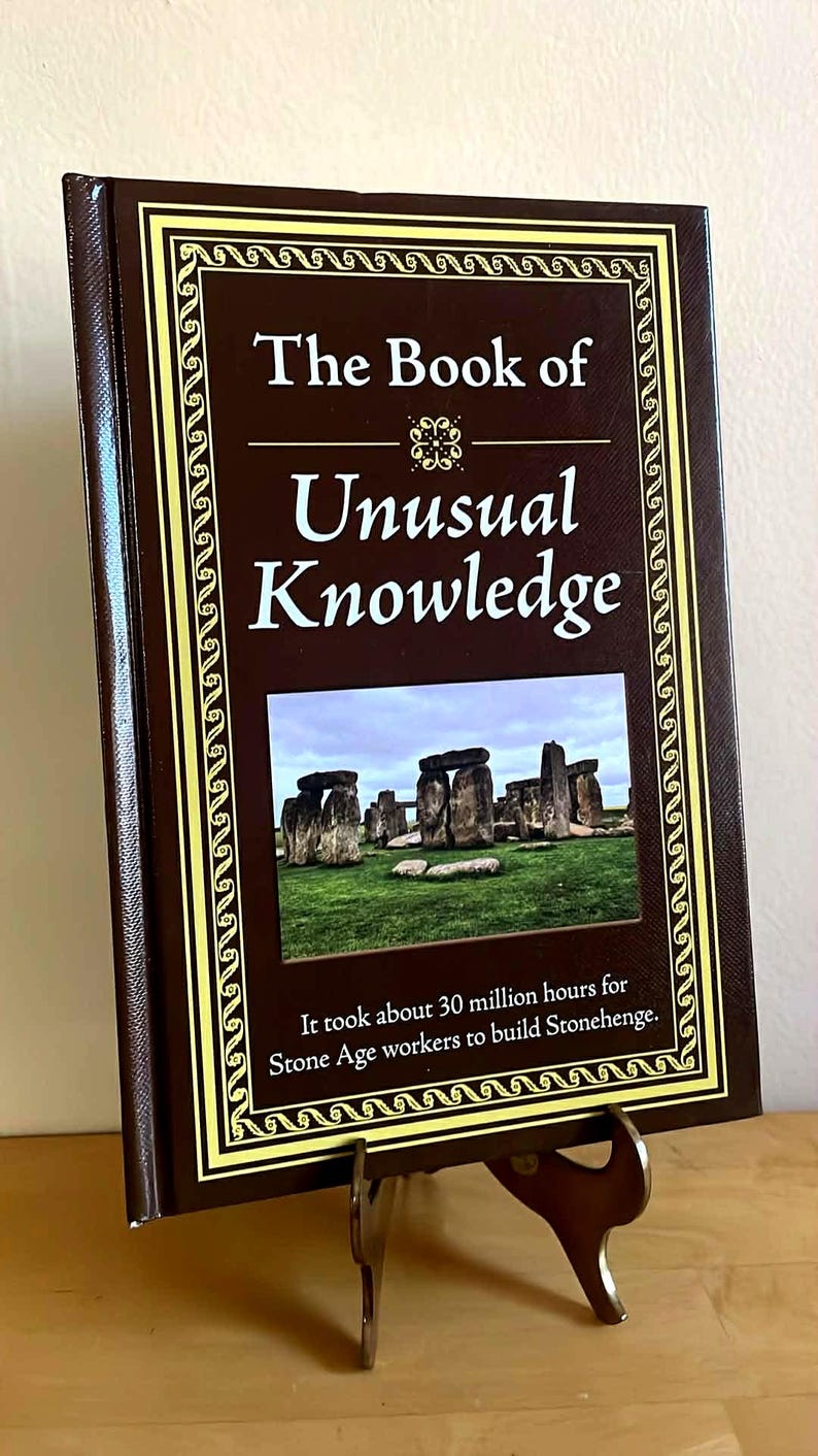Puede incluir: Un libro de tapa dura titulado "The Book of Unusual Knowledge" con una cubierta marr&oacute;n y un borde decorativo dorado. El libro presenta una imagen de Stonehenge y un texto que indica que se tardaron 30 millones de horas en construirlo.