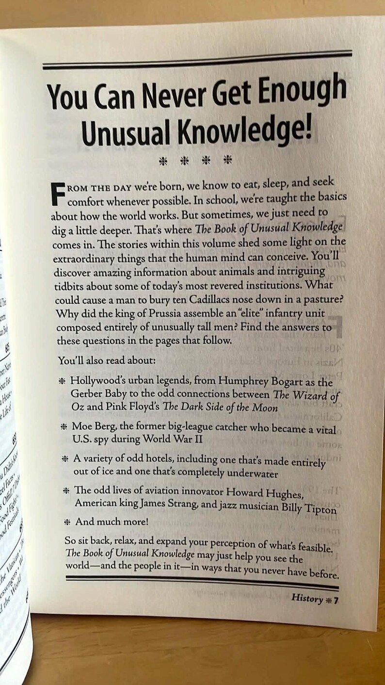 Puede incluir: P&aacute;gina de libro abierta con el t&iacute;tulo "You Can Never Get Enough Unusual Knowledge!". El texto aborda hechos e historias inusuales, incluyendo leyendas de Hollywood, hoteles extra&ntilde;os y figuras hist&oacute;ricas. El libro es parte de la serie "History".