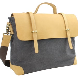 May include: A gray canvas messenger bag with a tan leather flap and straps. The bag has a top handle and an adjustable shoulder strap.