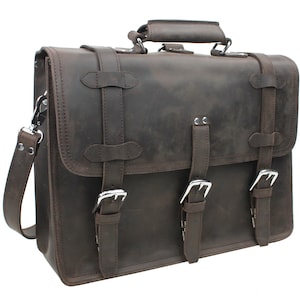 May include: A brown leather briefcase with a top handle and a shoulder strap. The briefcase has two buckles on each side and a flap with a buckle closure.