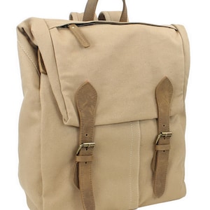 May include: A beige canvas backpack with brown leather straps and buckles. The backpack has a zipper closure and a flap with a buckle.