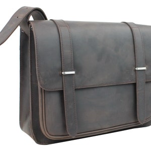 Puede incluir: Un bolso de mensajero de cuero marrón con dos correas ajustables y un cierre de solapa. El bolso tiene un aspecto desgastado y envejecido.