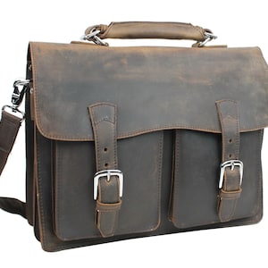 May include: A brown leather briefcase with a top handle and a shoulder strap. The briefcase has two front pockets with buckles.