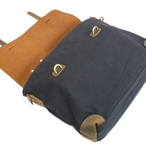 May include: A dark blue canvas messenger bag with brown leather accents and brass hardware. The bag is open and the inside is lined with brown leather.