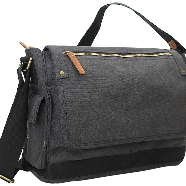 Op de afbeelding: Een grijze canvas messenger tas met een zwarte band en een ritssluiting bovenaan. De tas heeft een bruin lederen accent op de rits en een klein vakje aan de voorkant.