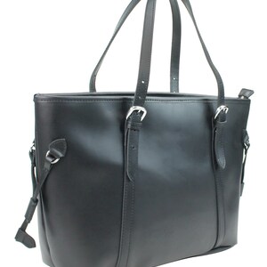 May include: A black leather tote bag with two adjustable straps and a zipper closure. The bag has a structured shape and a smooth finish.