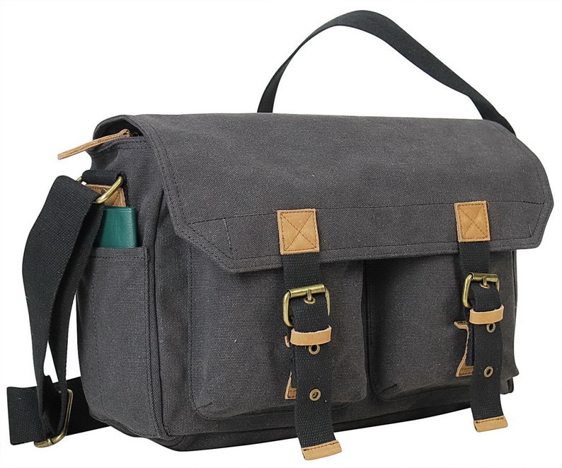 May include: A gray canvas messenger bag with brown leather accents and two front pockets secured with buckles. The bag has a black adjustable shoulder strap.