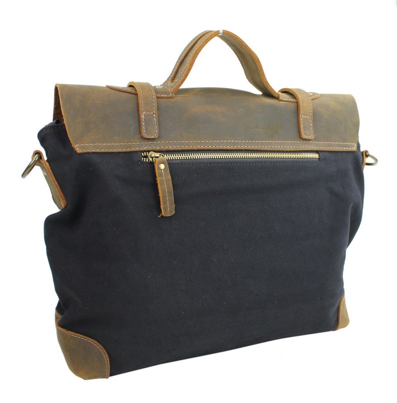 May include: A black canvas and brown leather messenger bag with a zippered pocket on the front. The bag has a top handle and a shoulder strap.