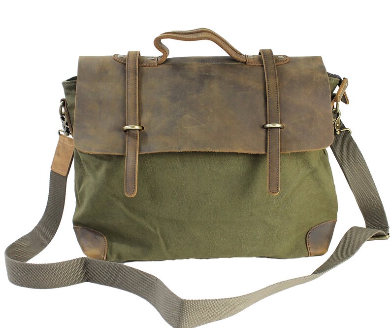 May include: A green canvas messenger bag with a brown leather flap and straps. The bag has a long adjustable shoulder strap.