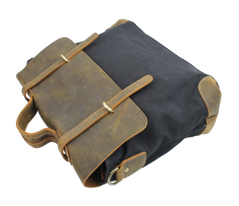 May include: A brown leather and black canvas messenger bag with a flap closure and adjustable strap.