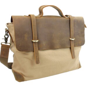 May include: A brown leather and beige canvas messenger bag with a top handle and adjustable shoulder strap. The bag has two leather straps with metal buckles.