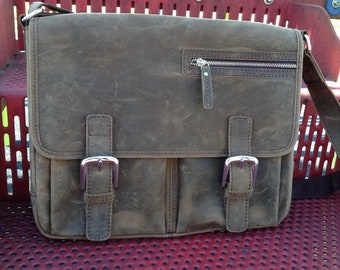 May include: A brown leather messenger bag with two buckles and a zippered pocket. The bag has a worn, distressed look.