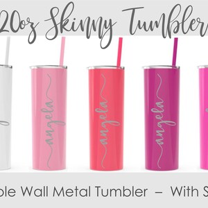 May include: A collection of five 20 oz. skinny metal tumblers in white, pink, coral, magenta, and fuchsia. Each tumbler has a matching straw and the name "angela" in a cursive font. The text "Double Wall Metal Tumbler - With Straw" is also present.