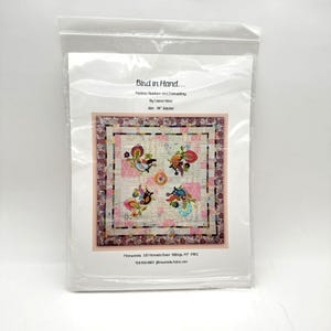 May include: A package for a quilt project titled "Bird in Hand." The quilt design features colorful bird and floral applique on a light background with pink geometric shapes. The quilt is 88 inches square.