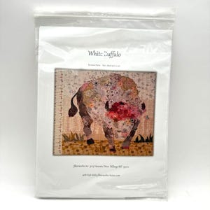 Peut inclure: Un paquet contenant une œuvre d'art textile intitulée "White Buffalo". L'œuvre représente un bison avec un motif floral dans les tons de rose, blanc et marron. Le paquet comprend également l'adresse et les coordonnées de Fiberworks Inc.