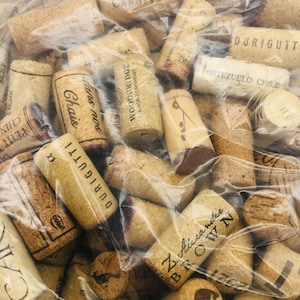 May include: A collection of used wine corks, many with printed text, including "DURIGUTTI", "WOODBRIDGE", and "Z. Alexander BROWN". The corks are various shades of brown and beige, some with dark brown markings, and are contained within a clear plastic bag.