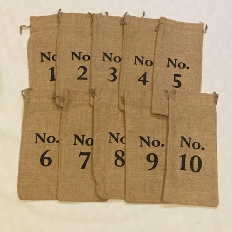 以下が含まれることがあります： 1から10までの黒い数字が印刷された、茶色のジュート製の袋が10個。袋は一列に並んでいます。