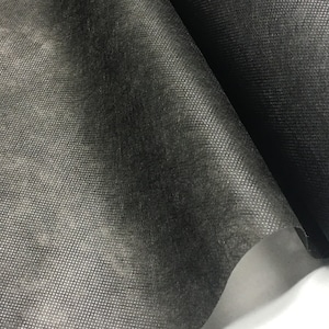 May include: Black woven fabric with a textured surface. The fabric is folded in half, showing the inside of the fold.