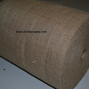 May include: A large roll of natural brown burlap fabric. The fabric is woven and has a rough texture. The roll is sitting on a white surface. www.burlapsupply.com