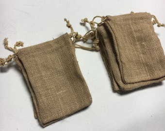 以下が含まれることがあります： 紐付きの小さな茶色の麻袋の束。袋は自然な織り生地で作られており、小さな贈り物や記念品を包装するのに最適です。
