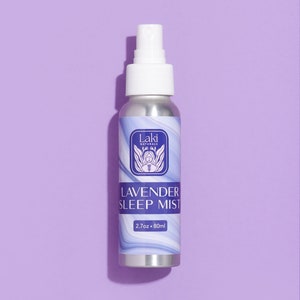 May include: A silver spray bottle with a white cap and a lavender label. The label says "Laki Naturals" and "Lavender Sleep Mist" with a 2.7 oz / 80 ml size.