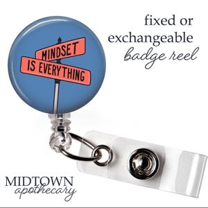Könnte beinhalten: Ein Badge-Roller mit blauem Hintergrund und dem Text "MINDSET IS EVERYTHING" auf einem Straßenschild. Die Rolle ist rund und hat ein einziehbares Kabel und einen weißen Kunststoffclip.