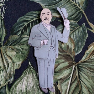 May include: A cartoon illustration of a man in a gray suit and a gray hat, tipping his hat. The man has a mustache and a bald head. The background is a dark green and black floral pattern.