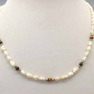 A lovely handmade single strand vintage jewelry necklace made with polished tiger eye beads with seed pearls and silvertone spacer beads