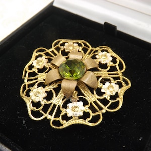 A superb early Czech round flower head vintage jewelry brooch in filigree goldtone metal set with a green center stone and enamel flowers