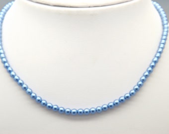 Un beau collier fantaisie à une rangée de petites perles d'imitation, fabriqué avec de fausses perles bleues brillantes et un fermoir argenté.