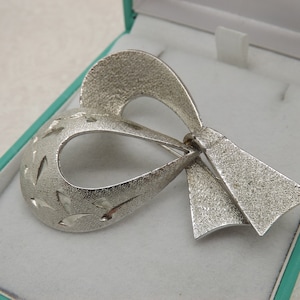 A fine Sphinx early period stylized bow vintage jewelry brooch made in openwork silvertone patinated and bright cut metal