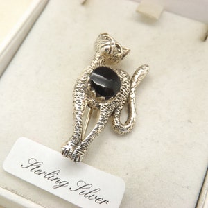 Può includere: Spilla a forma di gatto in argento sterling con finitura testurizzata e una grande pietra nera rotonda al centro. La spilla è presentata in una scatola bianca con l'etichetta "Sterling Silver".