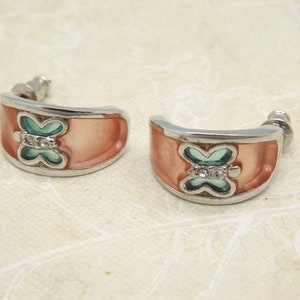 May include: A pair of silver hoop earrings with a peach-coloured enamel and a turquoise butterfly design with clear rhinestones.