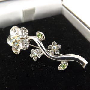 A beautiful handmade abstract flower stem vintage jewelry brooch made in silvertone metal and set with mixed coloured stones