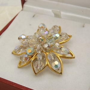 A lovely flower head costume jewelry brooch made in open work goldtone metal set with sparkly aurora borealis crystal faceted beads
