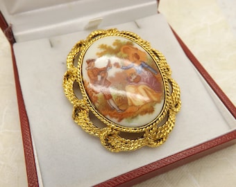 庭園を背景にカップルが描かれた磁器のプレートがセットされた、ゴールドトーンの金属製の美しいフラゴナール磁器の楕円形のヴィンテージジュエリーブローチ