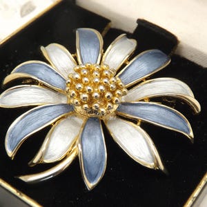 A fine enamel flower head costume jewelry brooch in goldtone metal in enamel in two shades of  blue colours